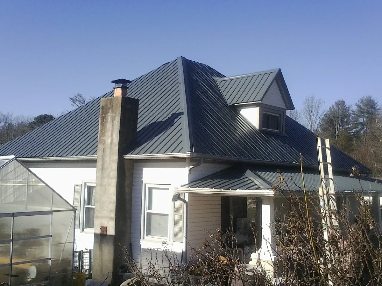 Dark blue standing seam metal roof on a white farmhouse with dormer — Slate & Tile Roof Repair by Roofing Brothers in Fanwood