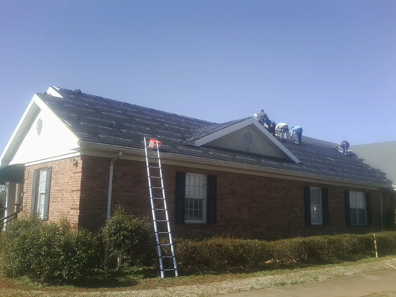 Crew tearing shingles off a brick ranch roof with a ladder set — Metal Roof Repair work by our crew in Fanwood