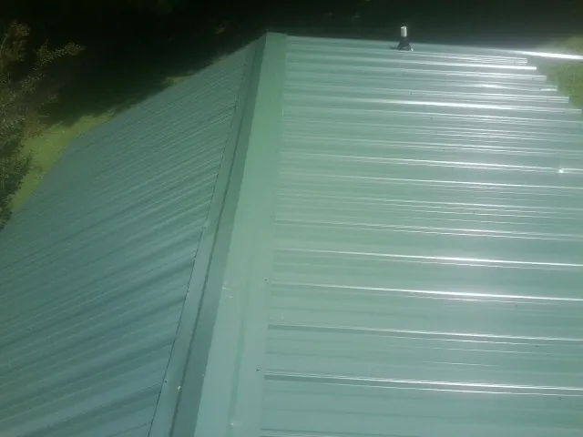 New green metal panels meeting at the ridge of a roof — Flat Roof Repair work by our crew in Fanwood