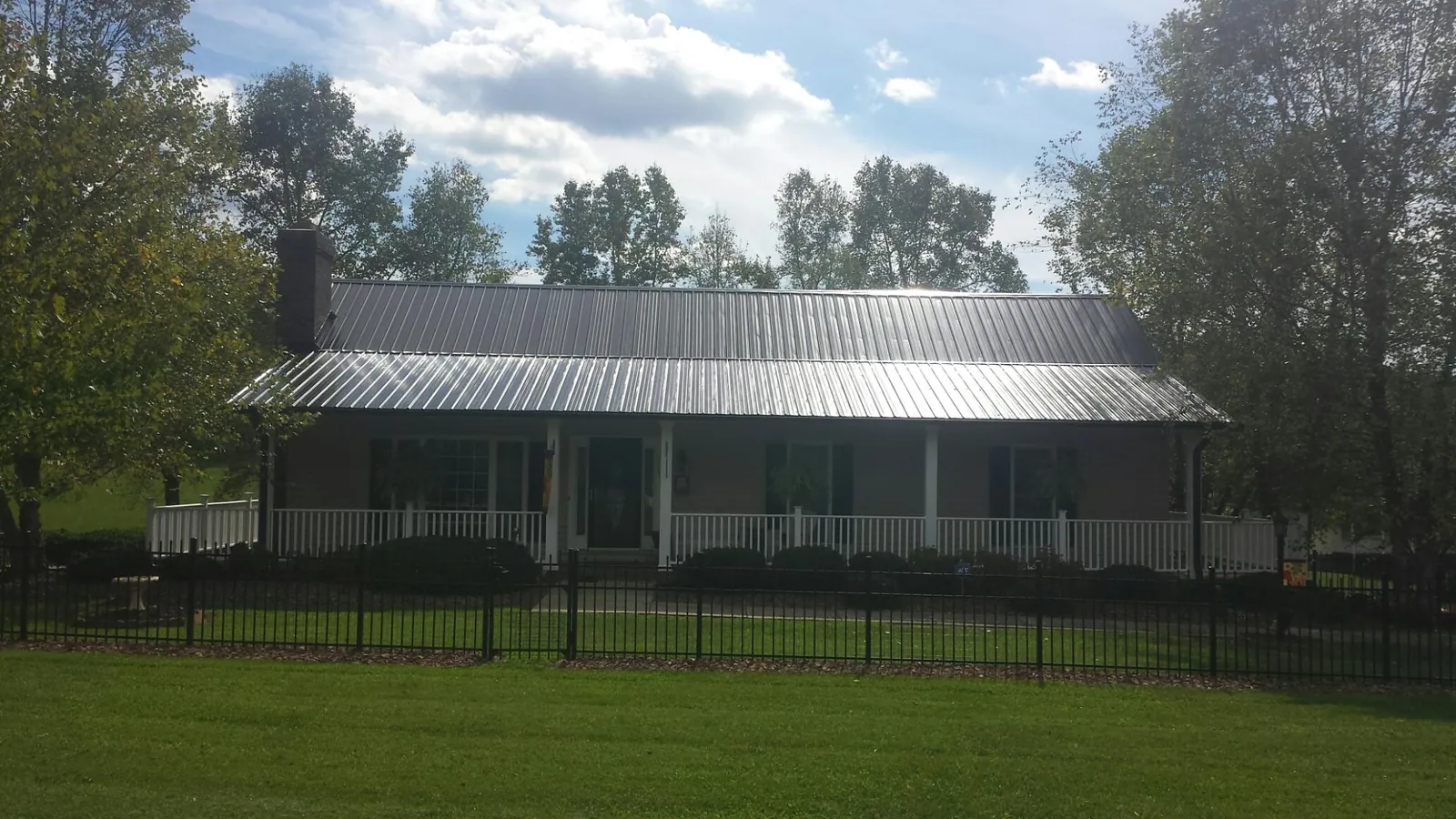 Gray metal roof on a brick ranch with a full width front porch — Gutter Guard Installation work by our crew in Fanwood