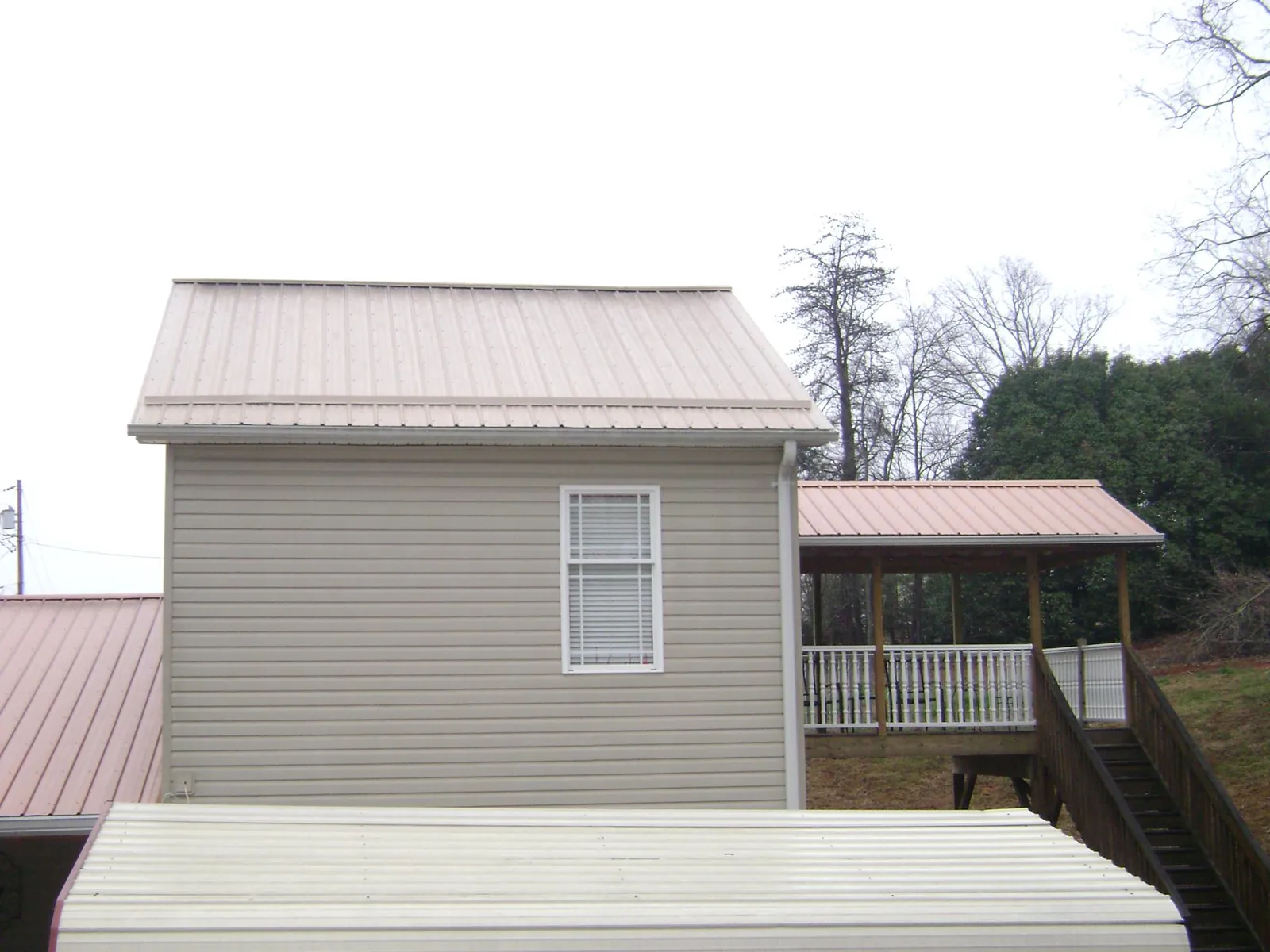 Tan metal roofs on a two story addition and attached porch, from a Roof Replacement job in Fanwood
