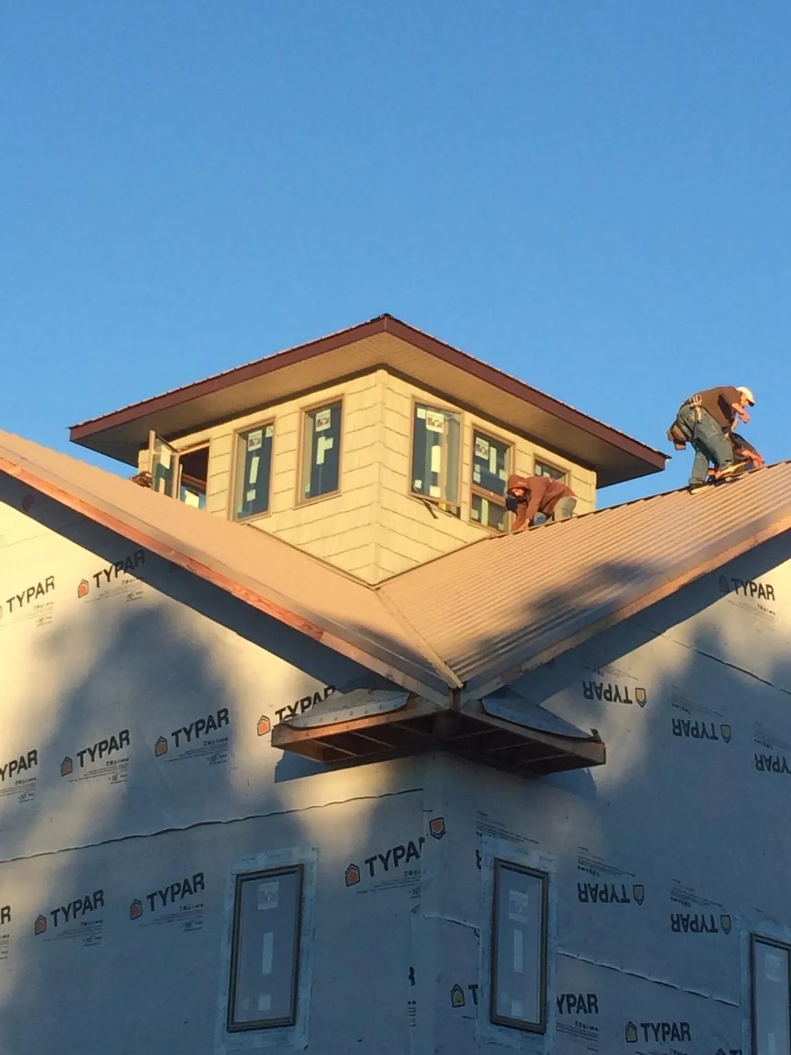 Roofers working around a rooftop cupola on a new metal roof at sunset — Roof Waterproofing in Fanwood by Roofing Brothers